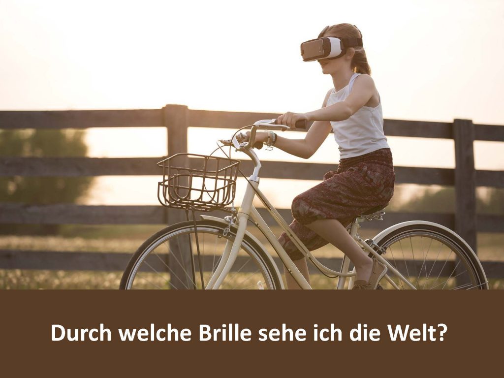 Foto eines Mädchens auf einem Fahrad mit einer VR-Brille mit dem Text "Durch welche Brille sehe ich die Welt?"